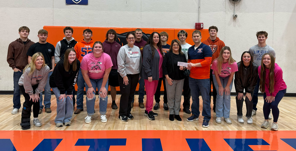 Members of the football and volleyball teams present a check from their Pink Night games to Pana Community Hospital.