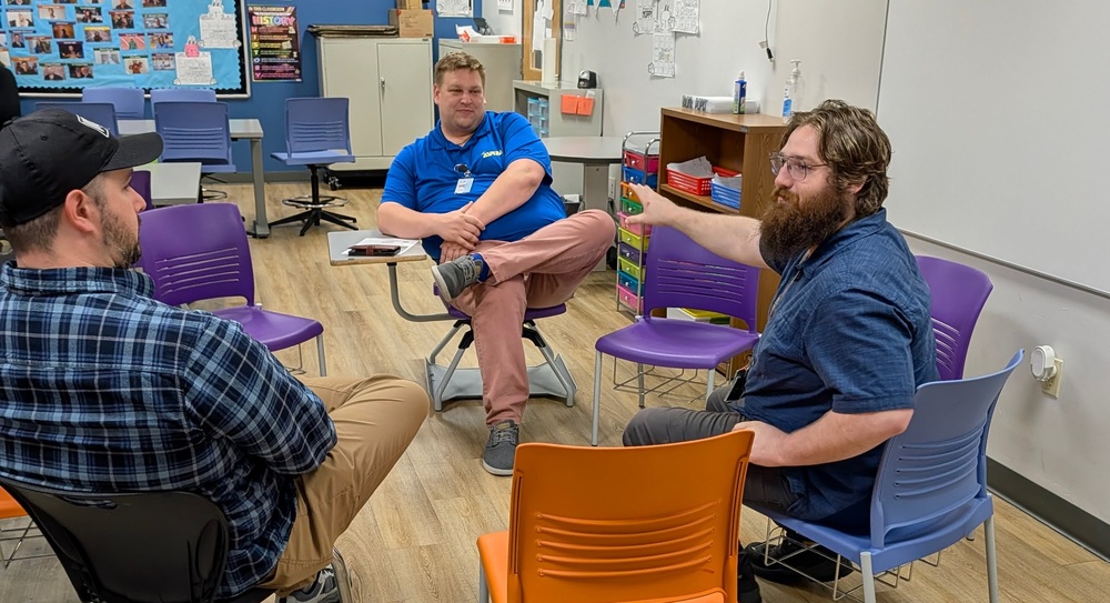 three men in chairs talking