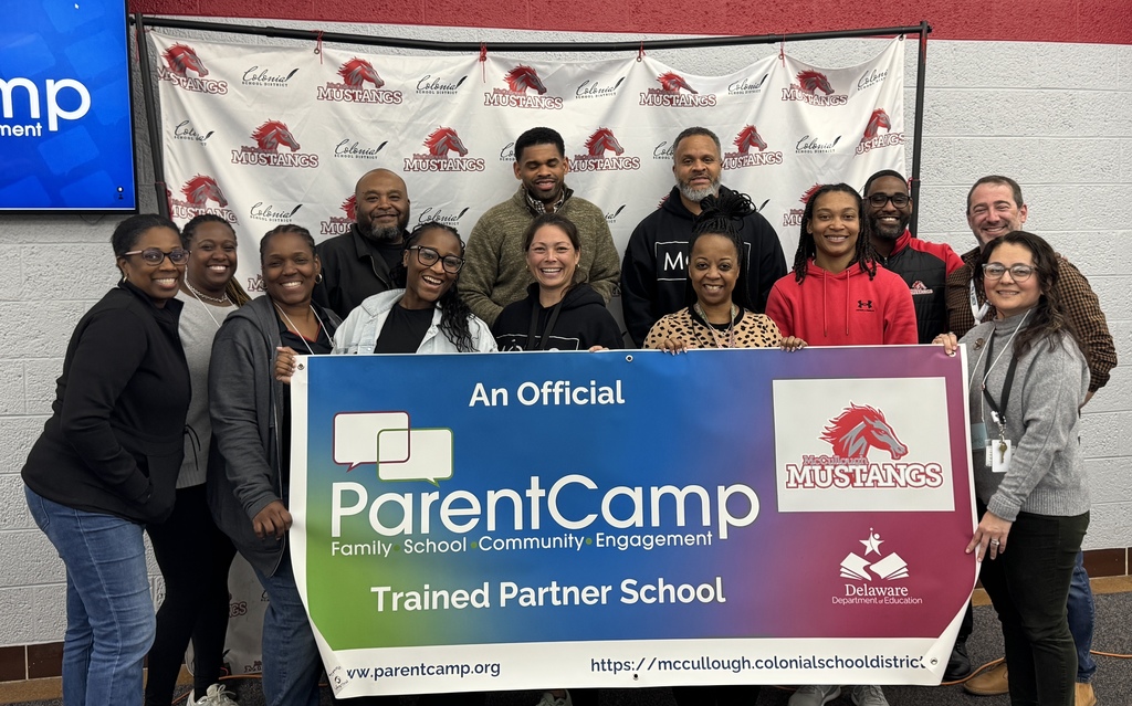 Group of adults holding a banner that reads "ParentCamp Trained Partner School" and a red horse logo.