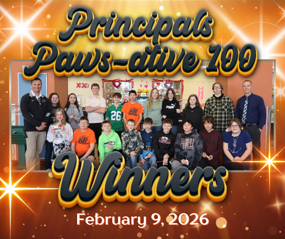 Students who won the Principals Pawsative 100 bingo board standing & kneeling in a cafeteria with the principals on either side.