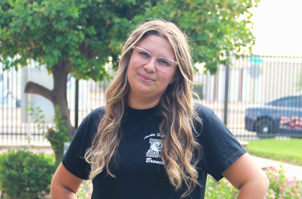 Sawyer with her signature smile surrounded by bushes and trees