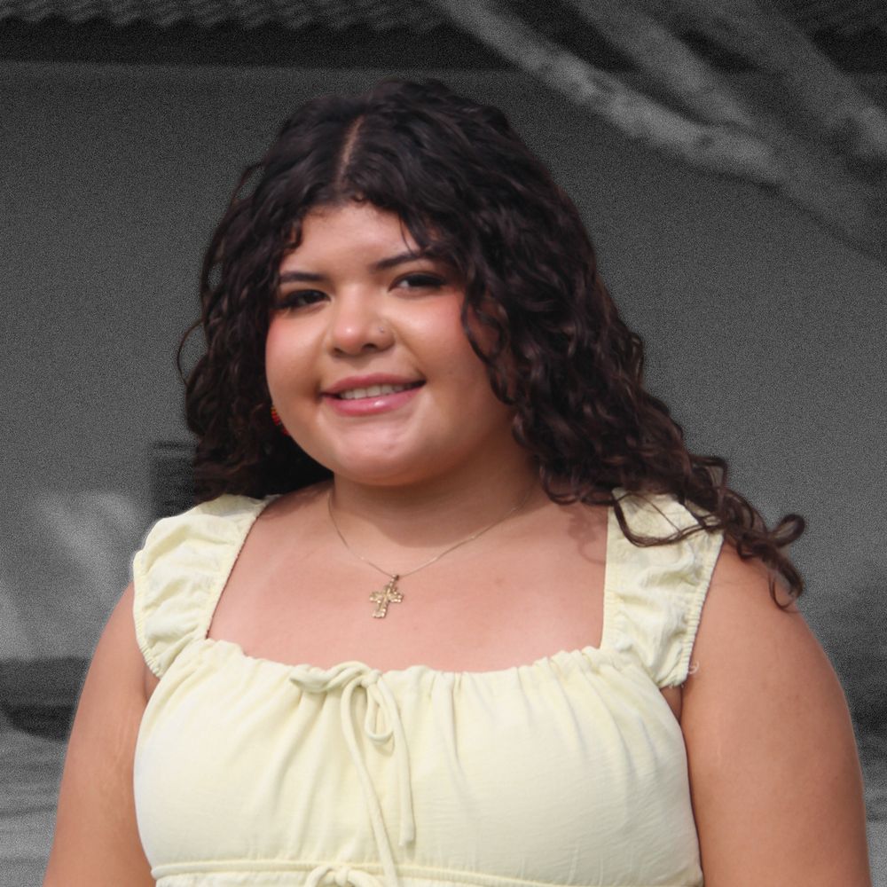 Ky-mani in a dress,  smiling with long curls of dark hair 