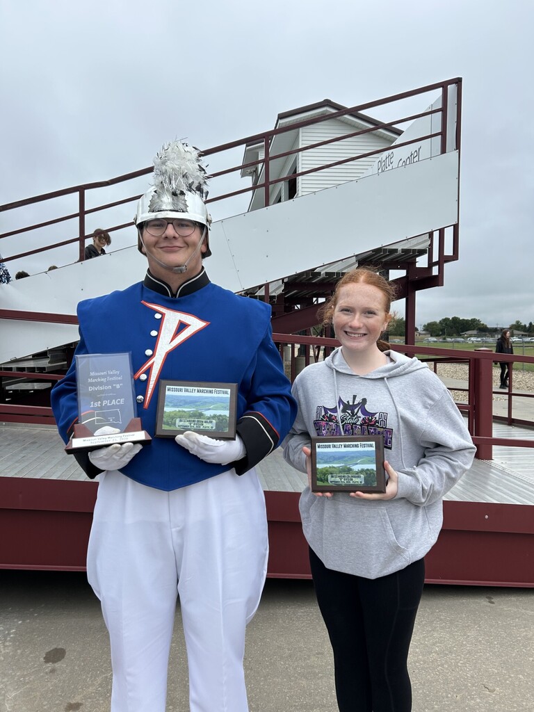 Drum Major Isaac Soulek (left) and Colorguard Captain Hayle Weisz holding the awards for best colorguard, best drum major, and a 1st place trophy for Marching Band