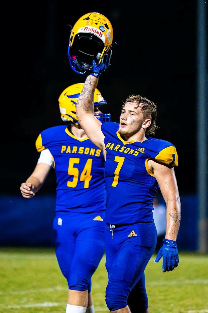 Photo by Sean Frye showing Chnadler Hentzen holding up his helmet after a touchdown.