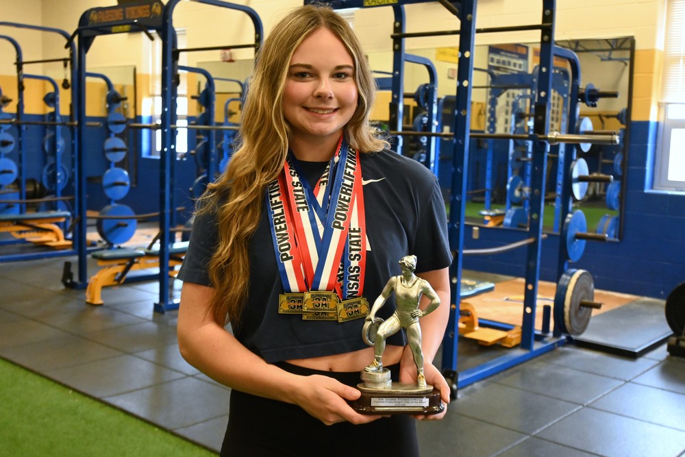 Autumn Sands wearing her medals and holding her trophy.
