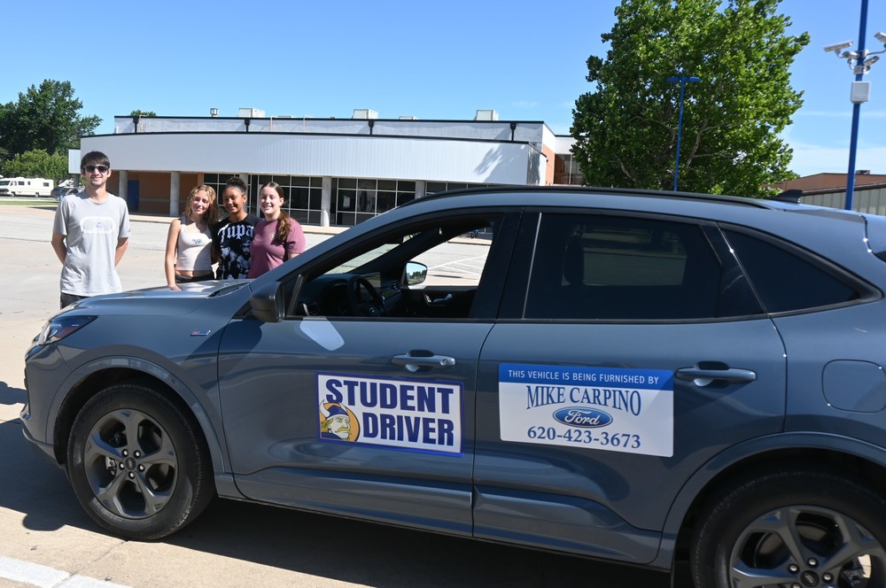 Wes Krull and three student drivers stand beside the drivers education car loaned by Mike Carpino Ford.