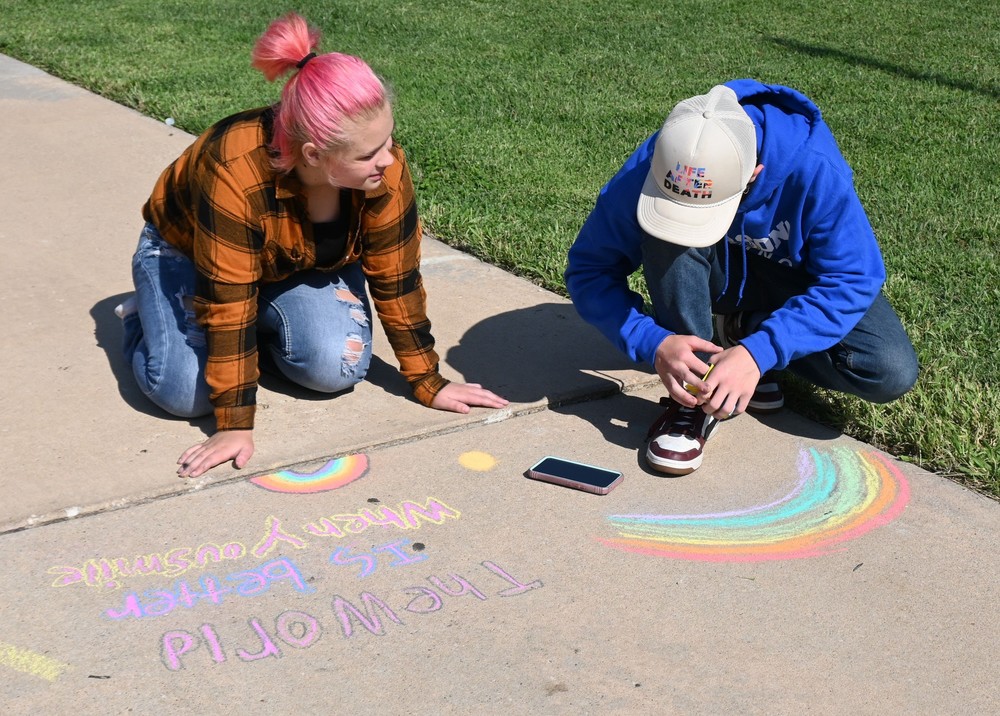 Students draw rainbows and write quotes in chalk