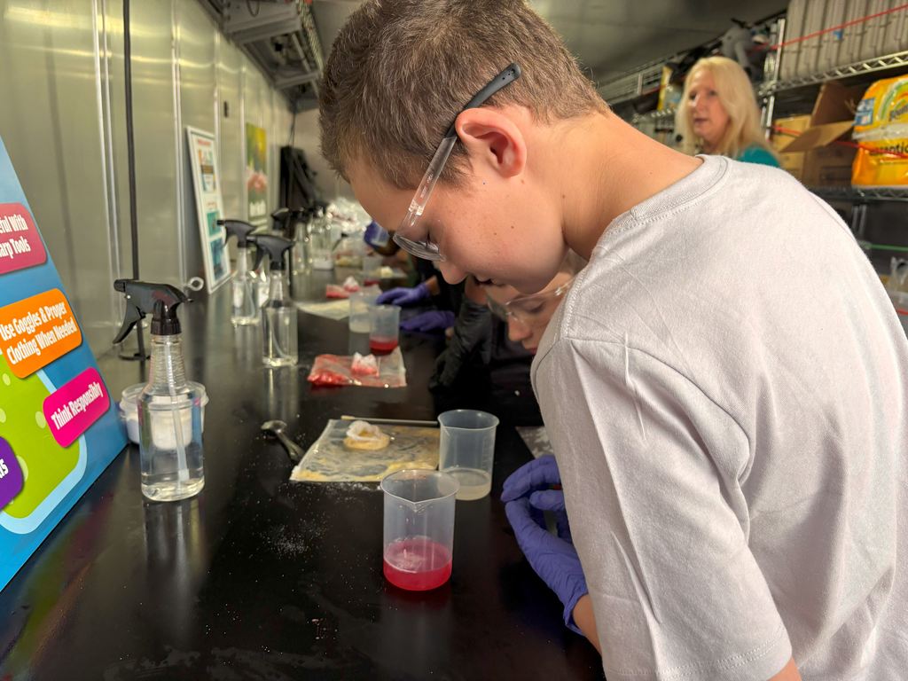 Students look in their cups to see strands of DNA forming.