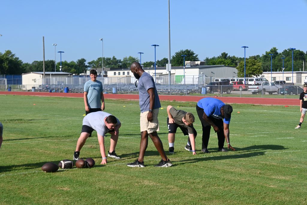 Coaches instruct players on proper stance.