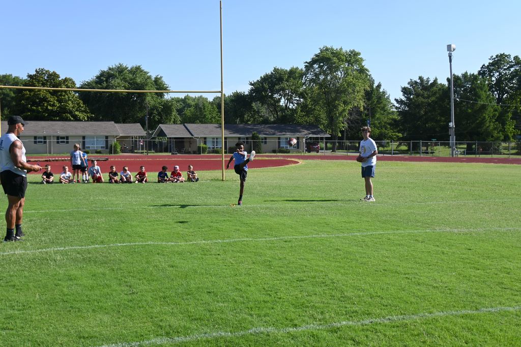 A boy kicks the football that was sitting on the holder.