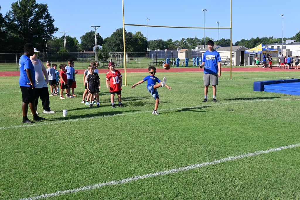 A boy drops the football and kicks it.