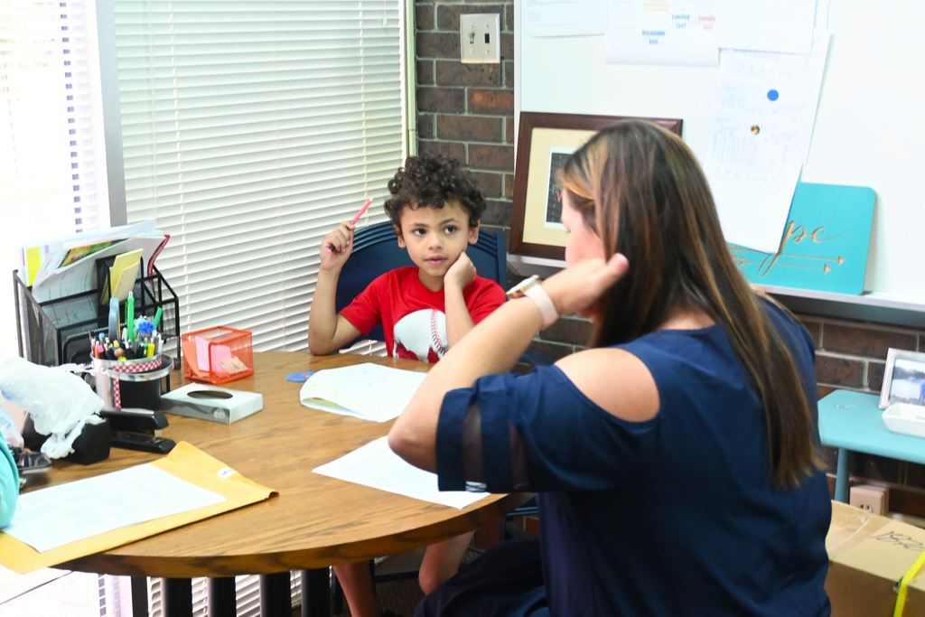 A little boy listen as Whitney Spencer asks him to circle specific letters during a kindergarten readiness assessment.