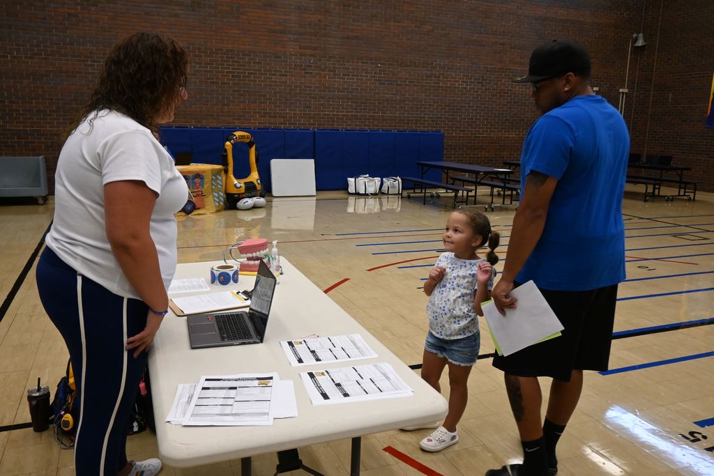 The school nurse visits with a new student and her father.
