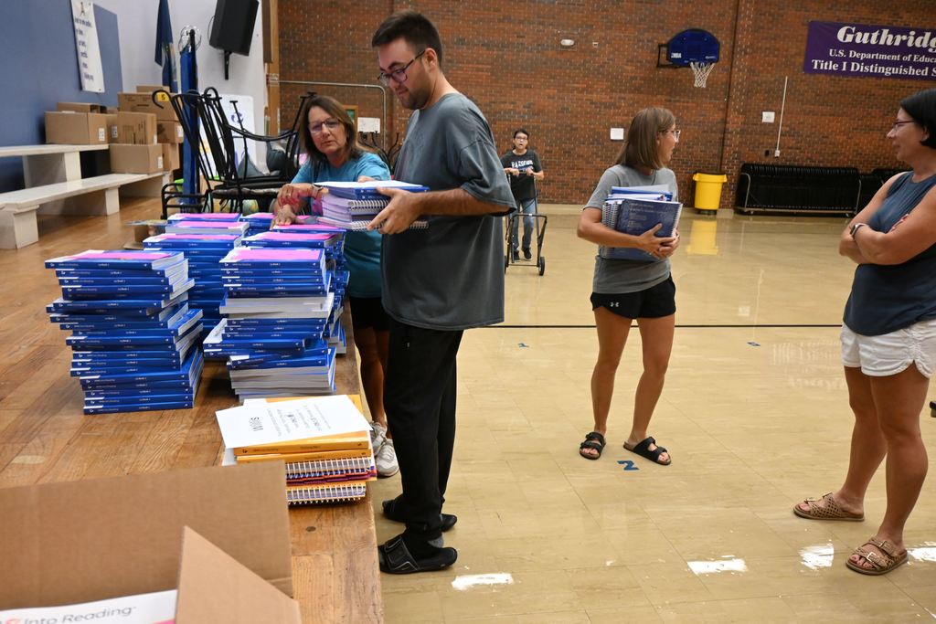 Michell Piva gives Cody Holmes workbooks for his students.