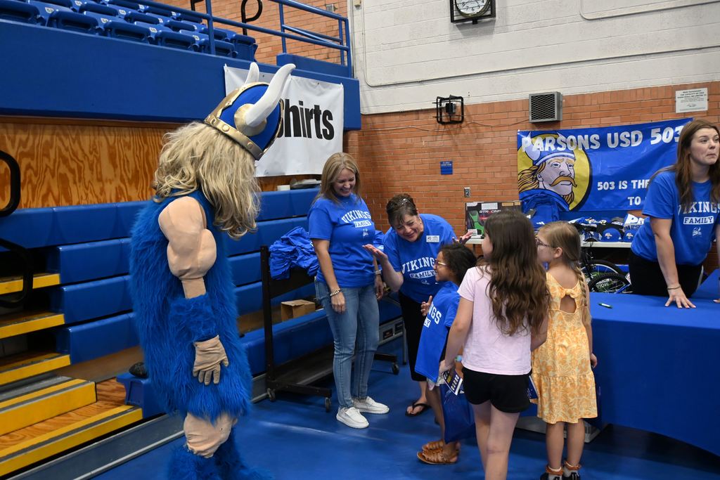 A little girl shows off the T-shirt she earned to Victor the Viking.