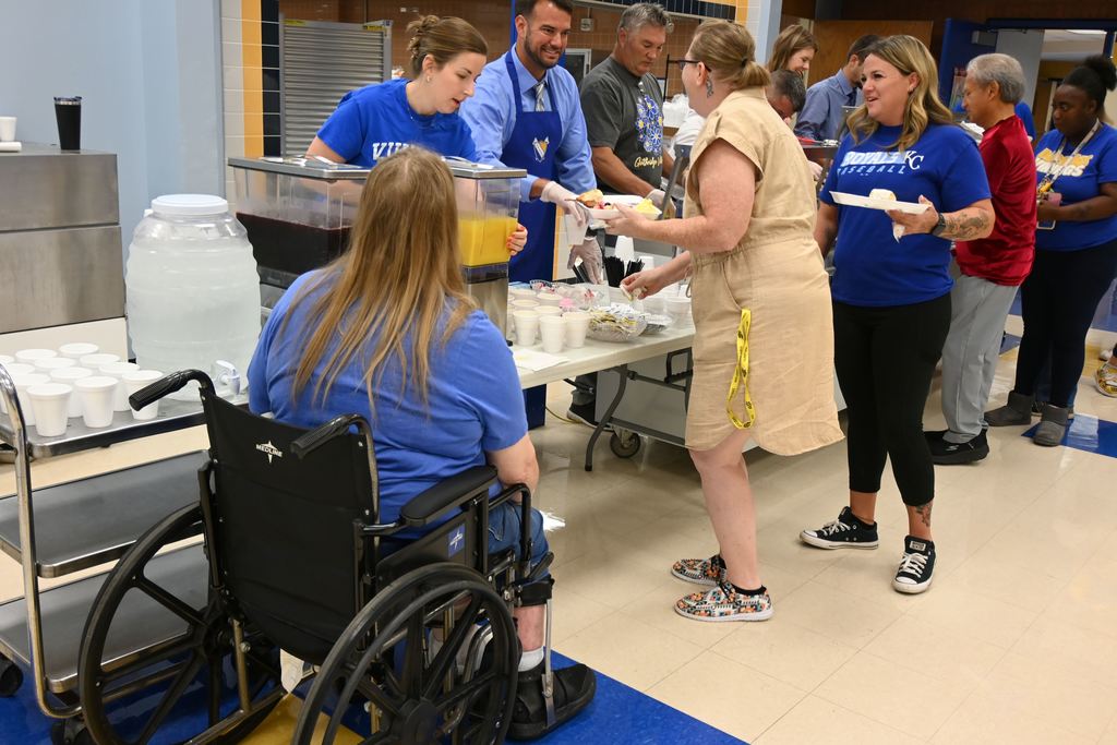 Administrators and board members serve staff members breakfast.