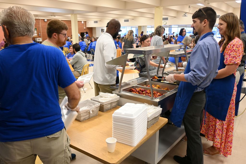 Administrators and board members serve staff members breakfast.