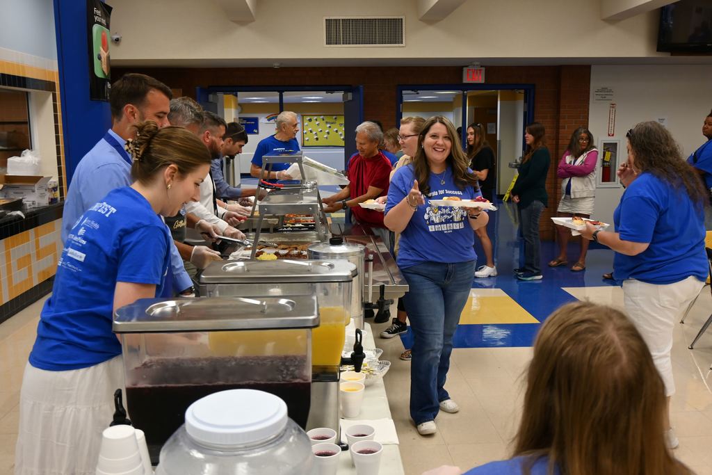 Administrators and board members serve staff members breakfast.
