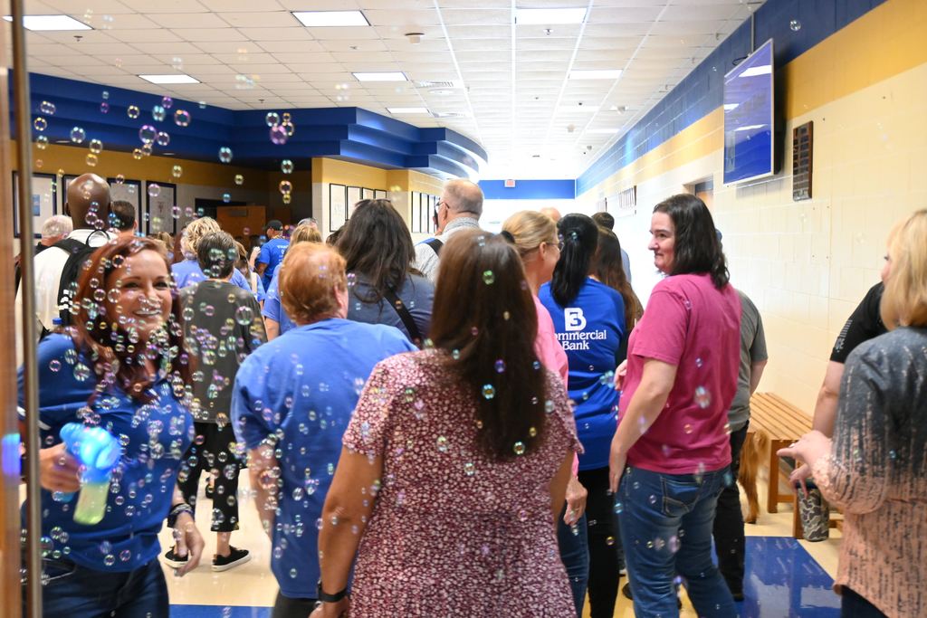 Board Member Kala Green greets staff with bubbles and a smile as they enter the auditorium for professional developmenet session.