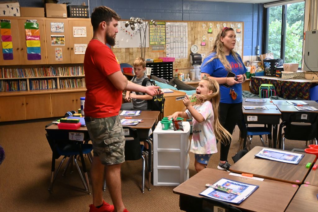A little girl ibouces with excitement over a gift she received from her teacher.