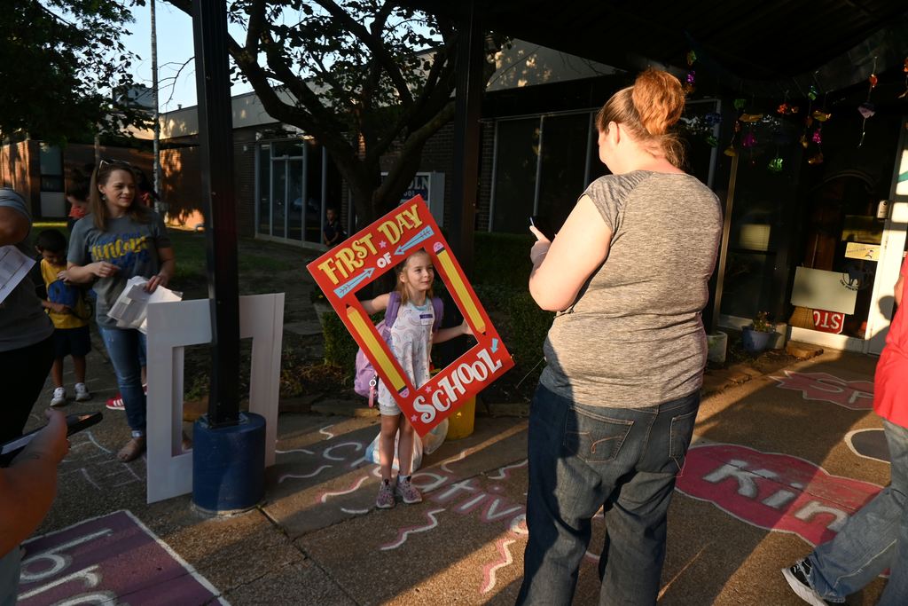 A little girl gets ready for her monm to rake her picture.