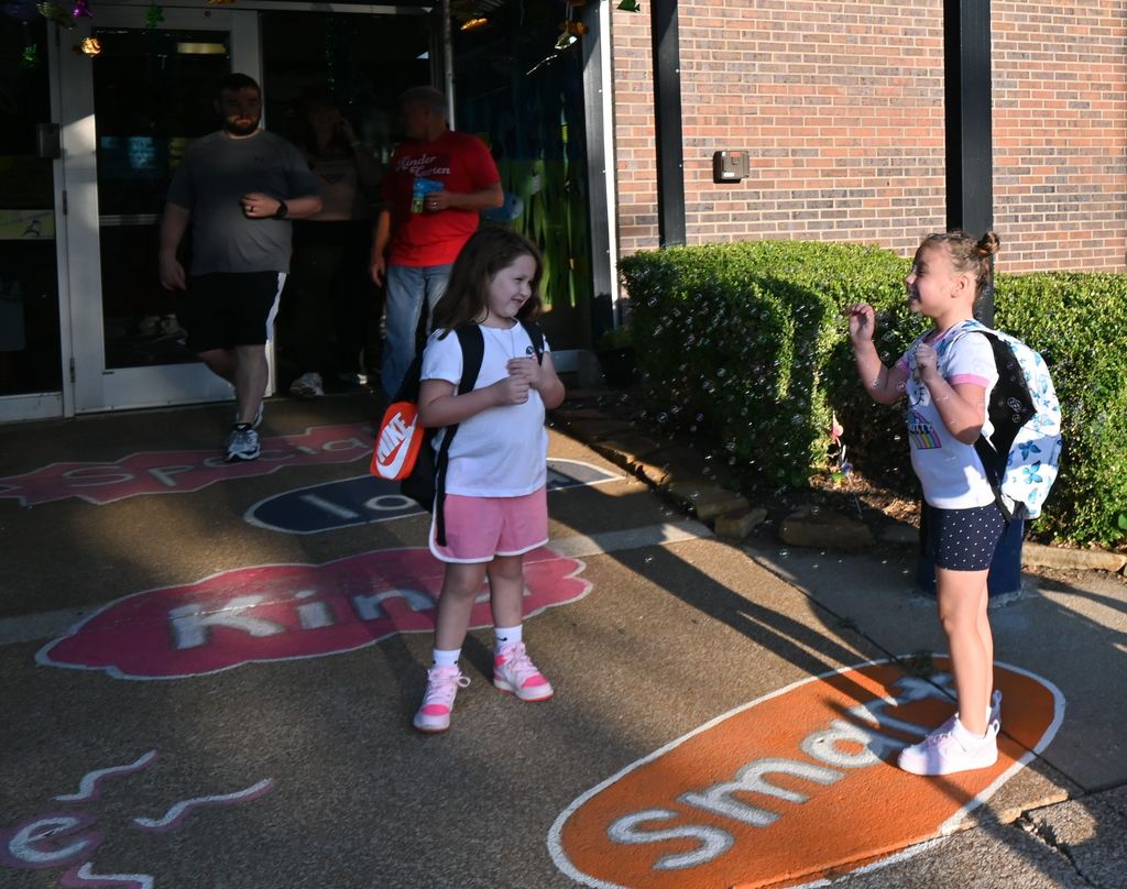 a girl plays in bubbles while talking to a friend.
