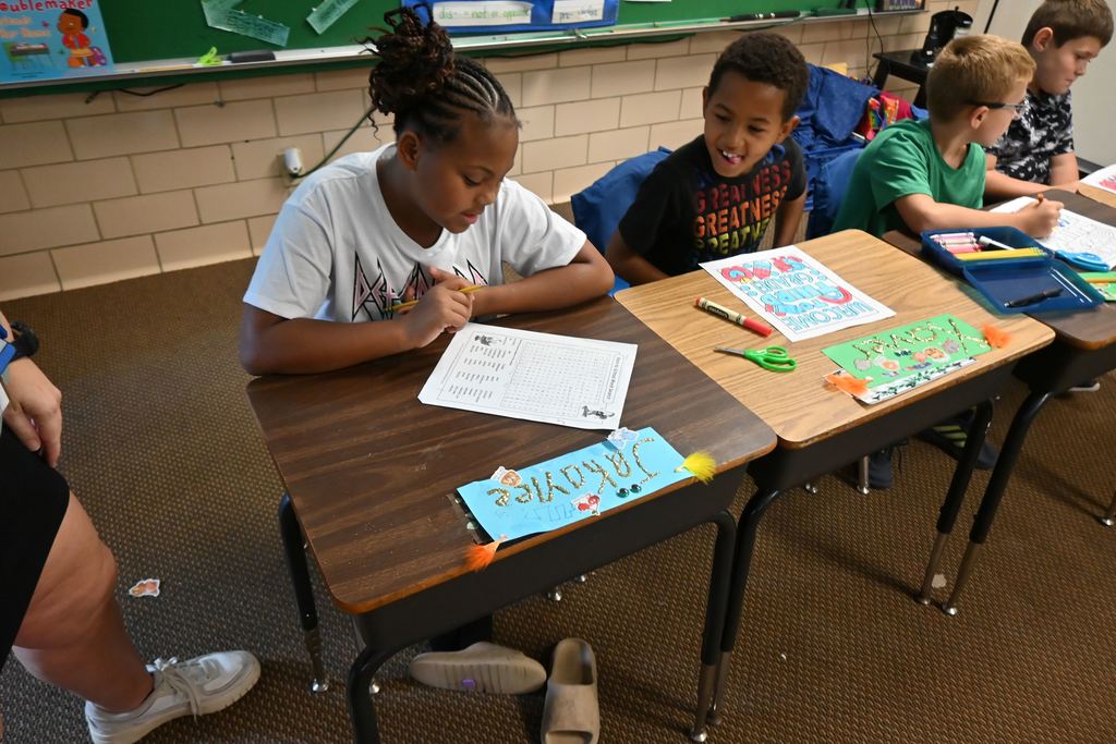 A girl does a word search after decorating her name plate.