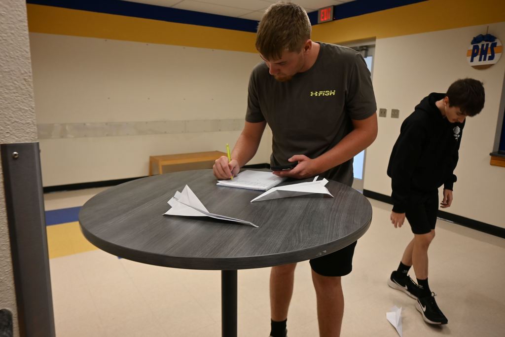 A teammate records data while another walks off the distance their airplane flew.