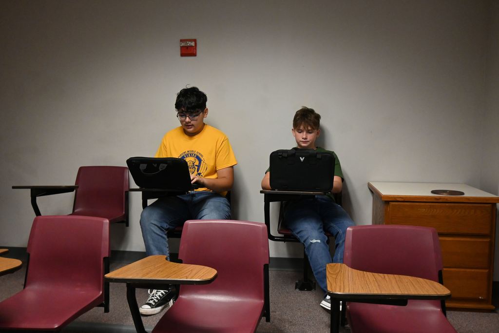 Two students work together on a slide show regarding electrical safety.