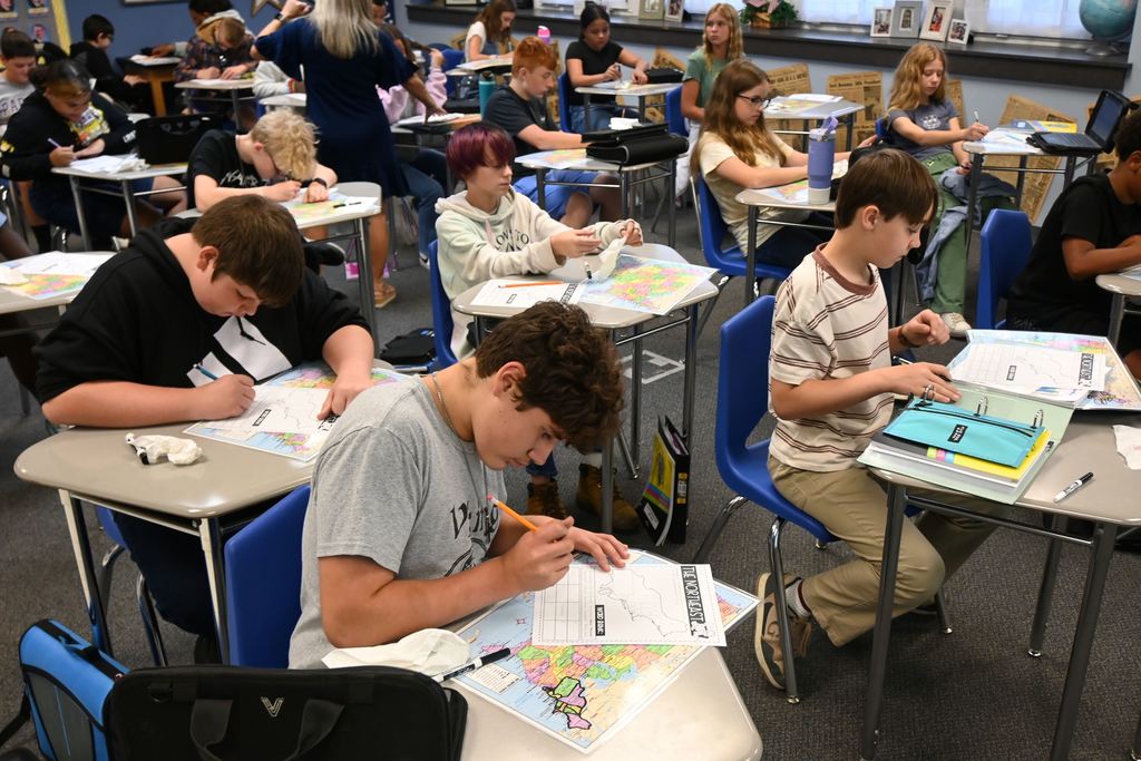 Geography students make notes on a study sheet from a map.