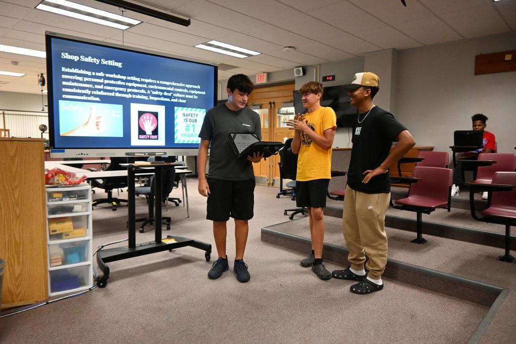 A group of three students begin their presentation on workshop safety to the rest of the class.