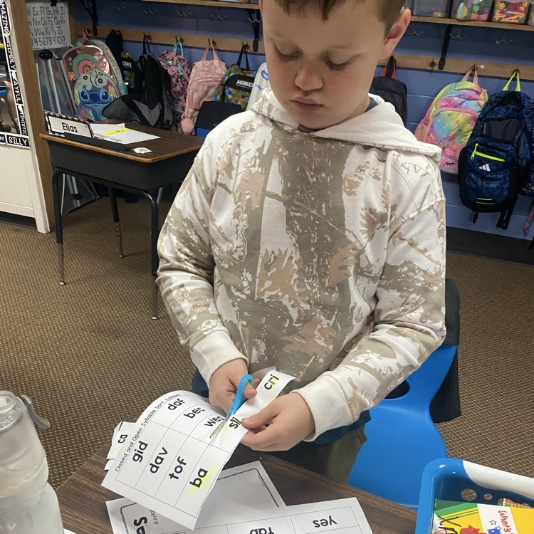 student cutting out slips of paper to sort syllable types