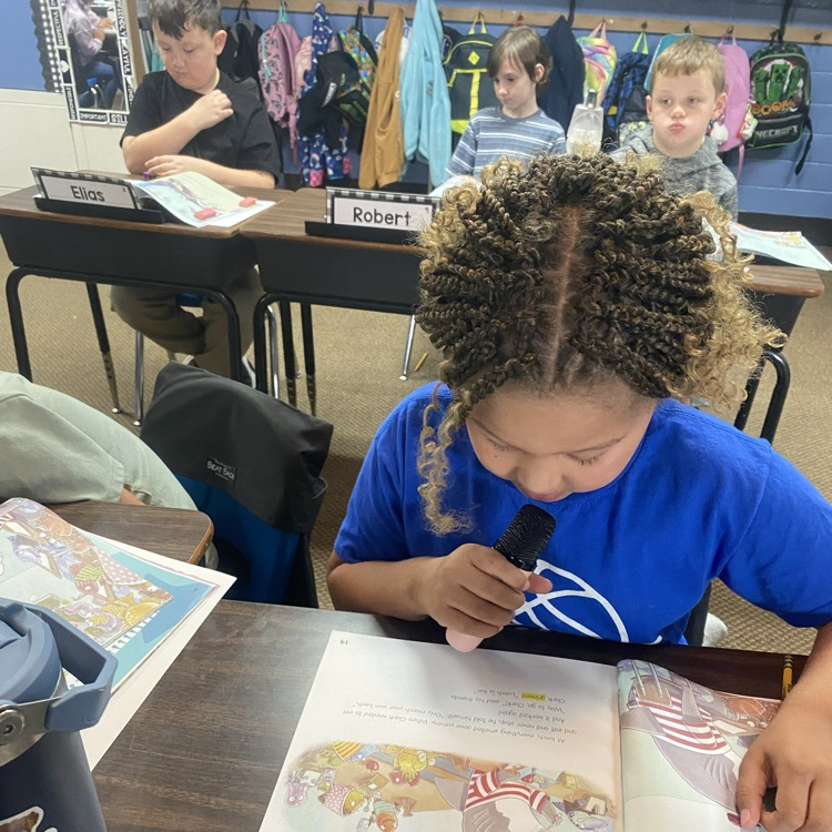 A student reading from a textbook using a microphone