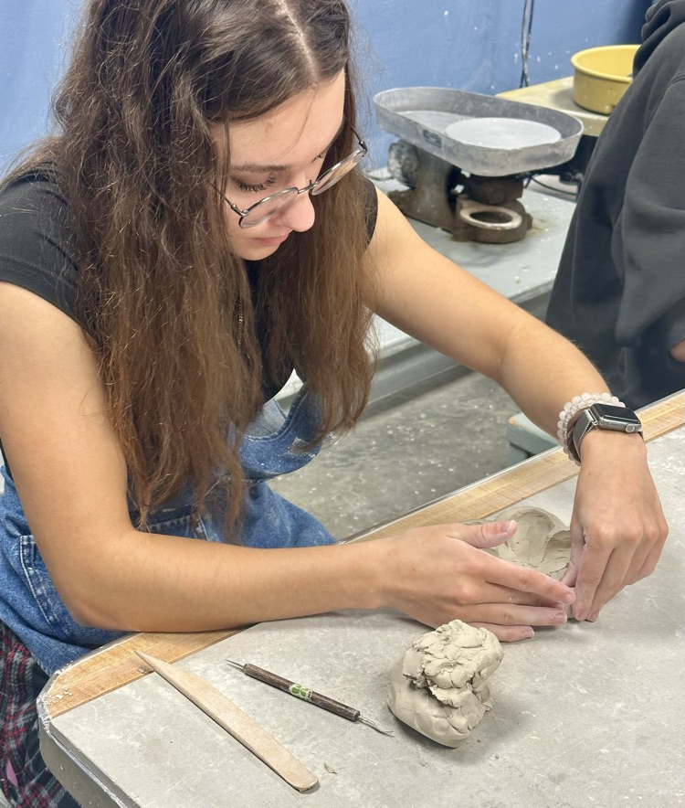 Student working hard on reshaping her flower trinket bowl.