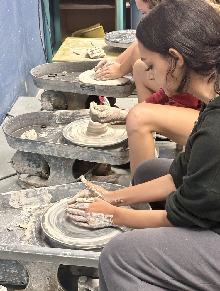 Students getting some practice on the wheel by learning how to throw clay with Miss.Vincent