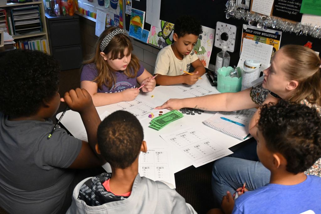 Students in Mrs. Pollards class work with play money to find specified amounts using bills and change.