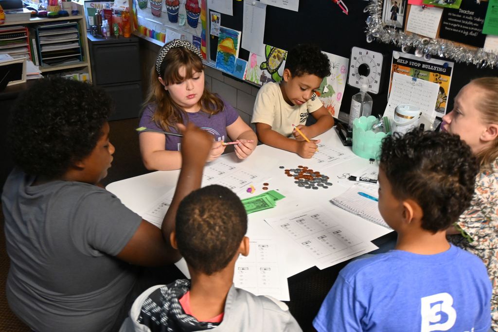 Students in Mrs. Pollards class work with play money to find specified amounts using bills and change.
