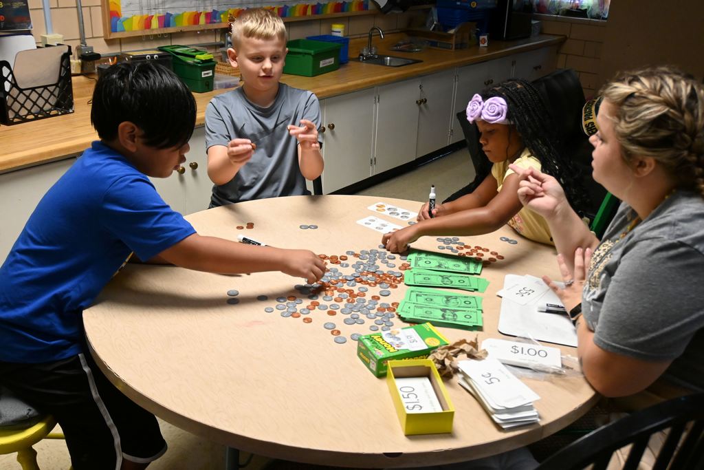 Students in Mrs. Pollards class work with play money to find specified amounts using bills and change.