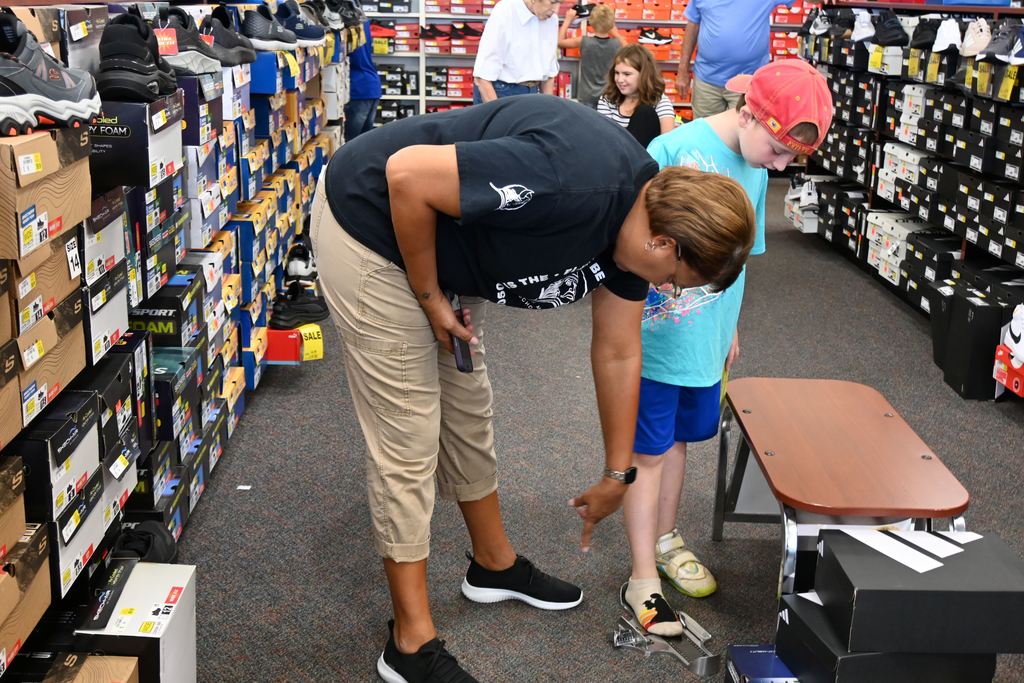 Susan Hill measures a student's foot to see what size shoe he wears.