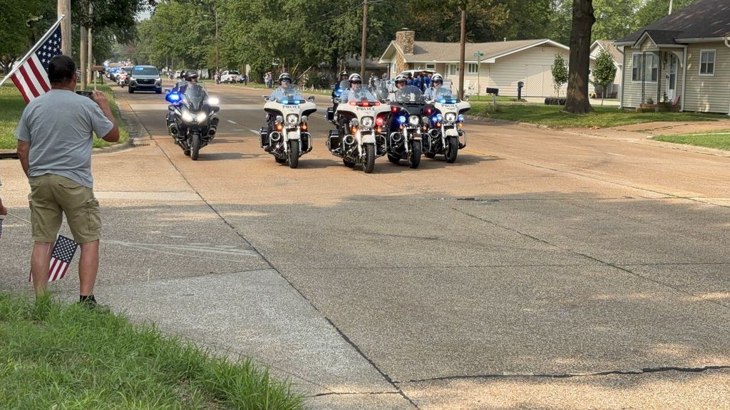 Small groups of USD 503 family gather along 32nd street to honor fallen officer Hunter Simoncic as his funeral procession goes by.