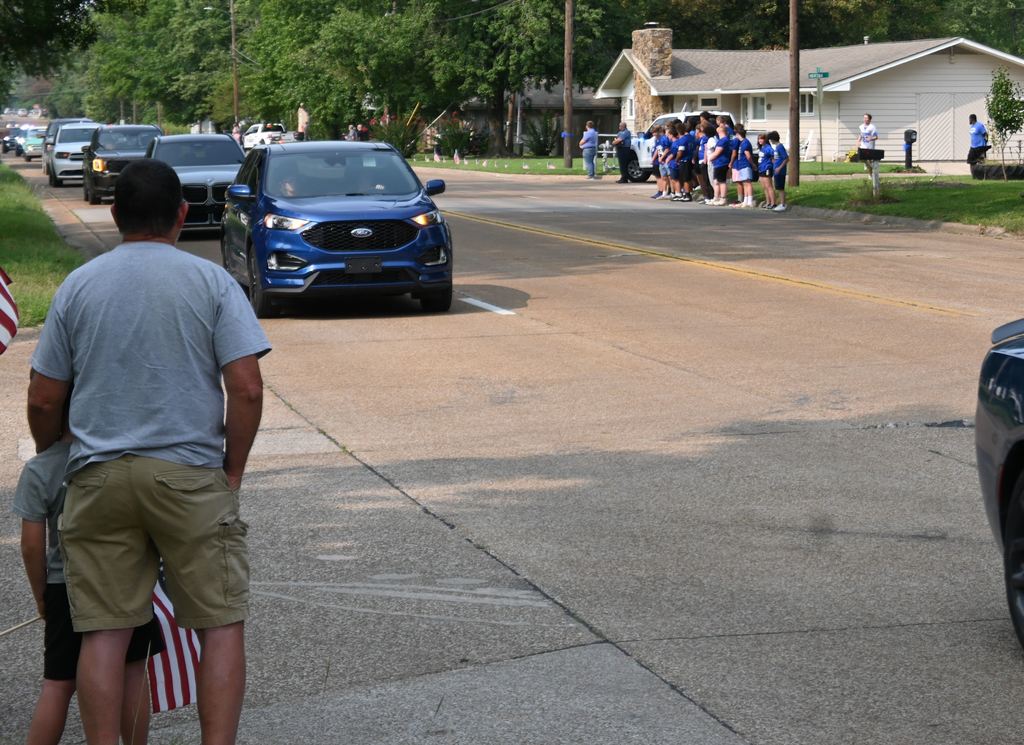 Small groups of USD 503 family gather along 32nd street to honor fallen officer Hunter Simoncic as his funeral procession goes by.
