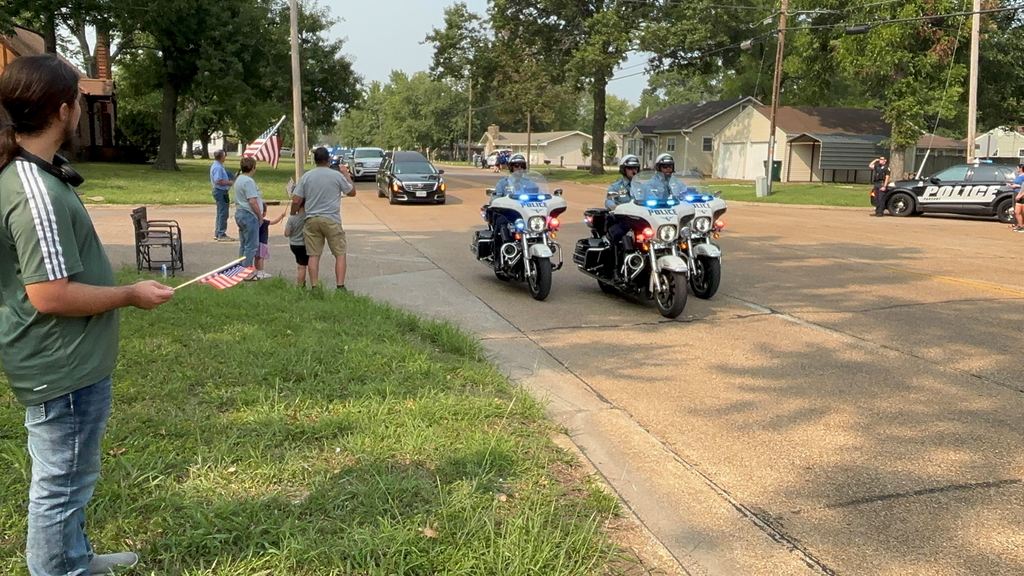 Small groups of USD 503 family gather along 32nd street to honor fallen officer Hunter Simoncic as his funeral procession goes by.