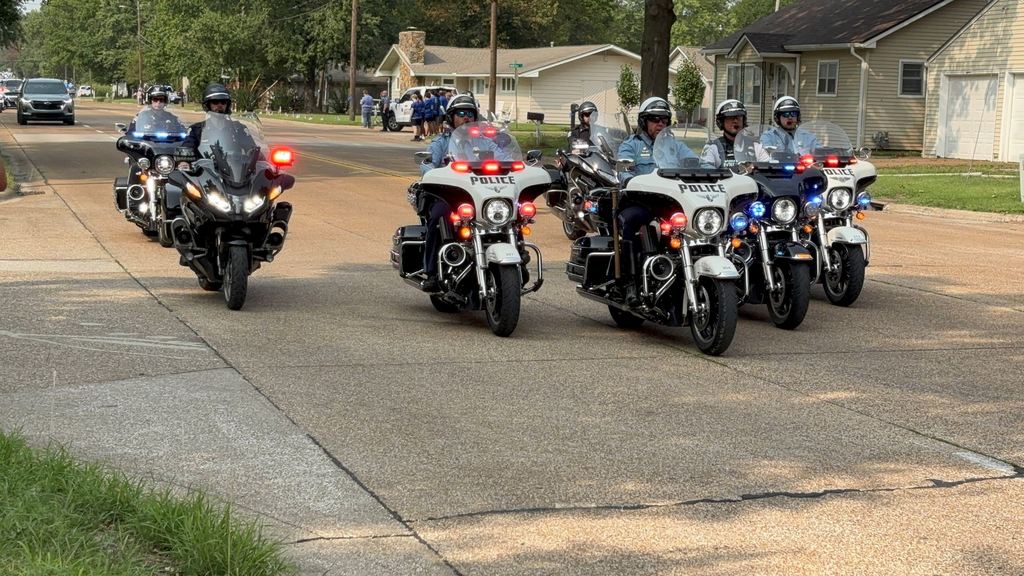 Small groups of USD 503 family gather along 32nd street to honor fallen officer Hunter Simoncic as his funeral procession goes by.