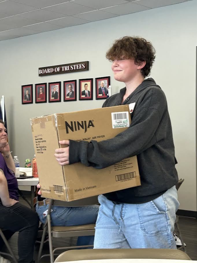 A student heads to her table with a Ninja Air Fryer she won.