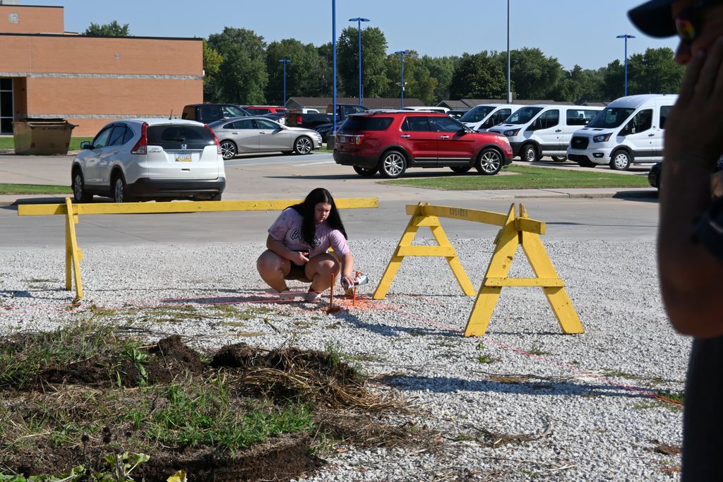 A student spraypaints stakes so people can see them.