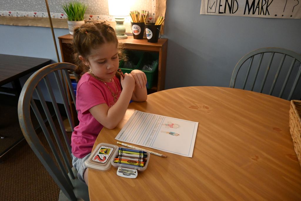 A little girl draws a picture to go with her sentence ,  "My techr loves oliv uss."