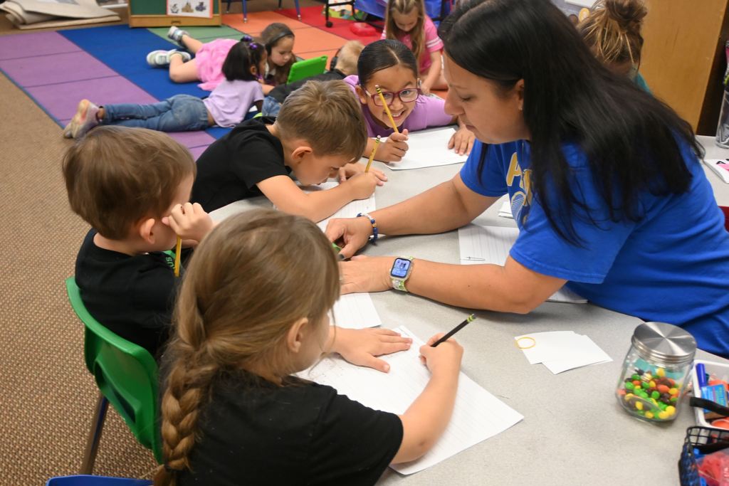Mrs. Kennett helps a student with where his letters need to met the lines.