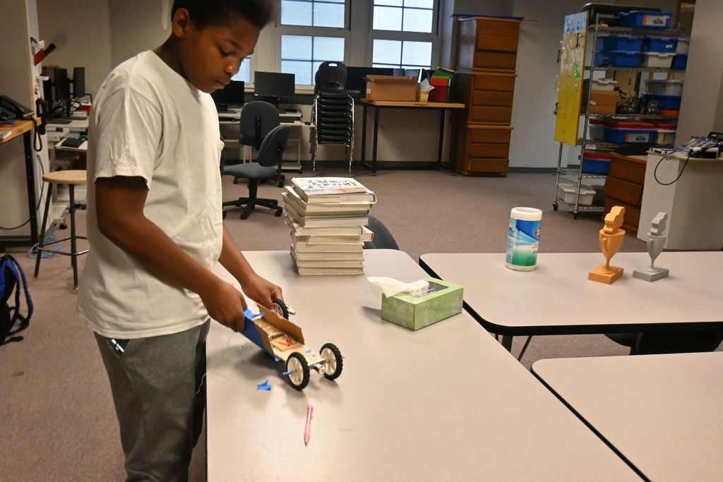 A student attempts to make repairs to his car in rder to be able to race it.