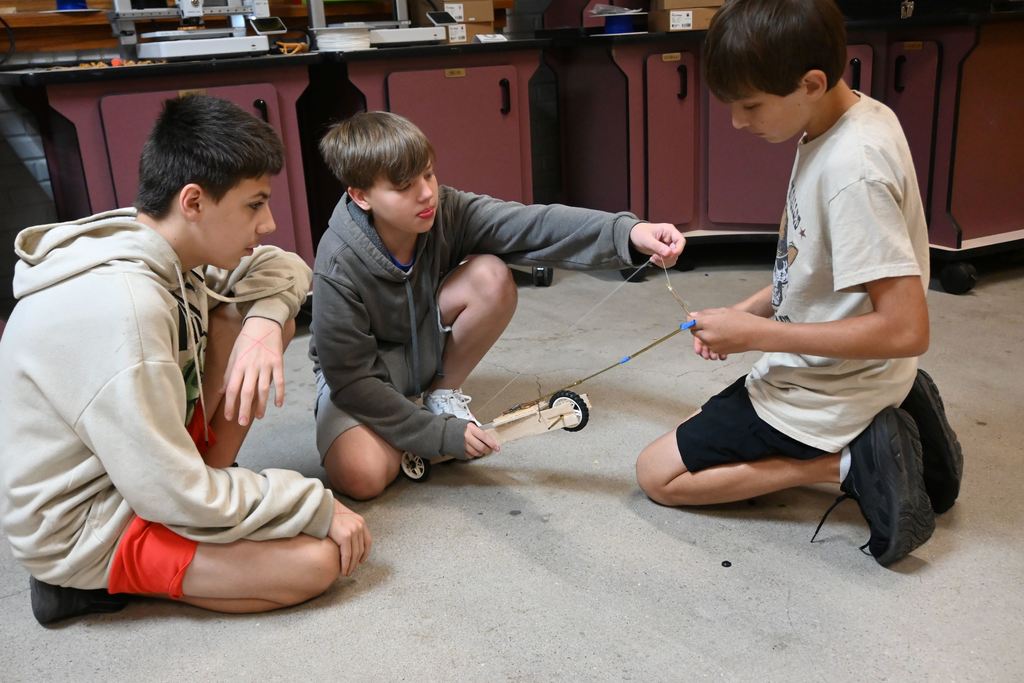 Three boys work on their car.