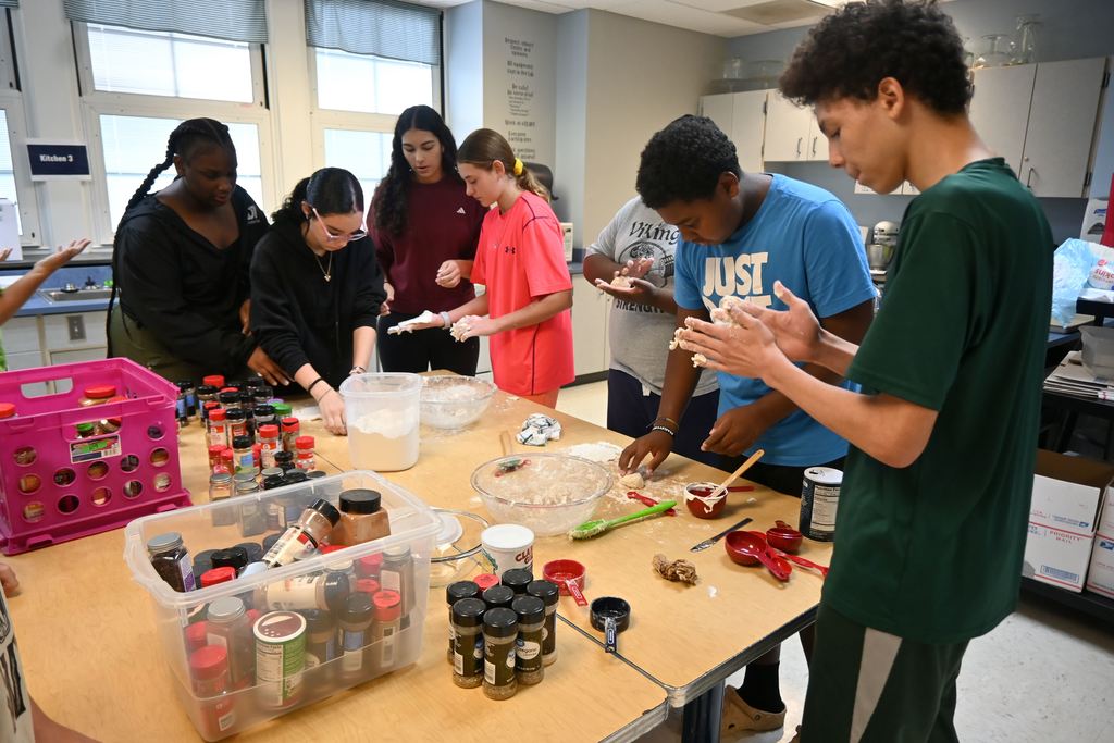 Students make balls of dough they flatten out to make pita bread.